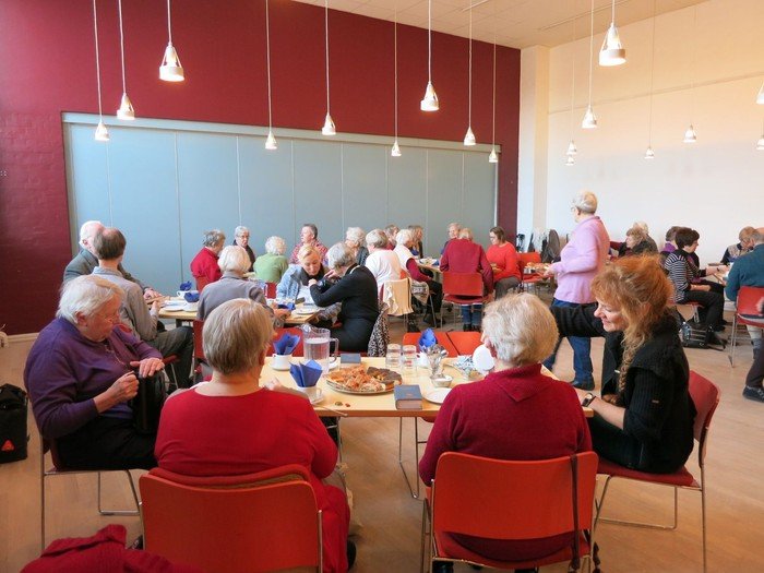 Salen fyldt med ældre mennesker som får kaffe og kage